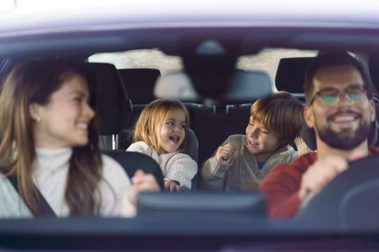 A cute boy and a his little sister enjoy traveling by car with their parents